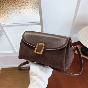 Brown vintage shoulder bag with gold buckle and textured finish in minimalist indoor setting