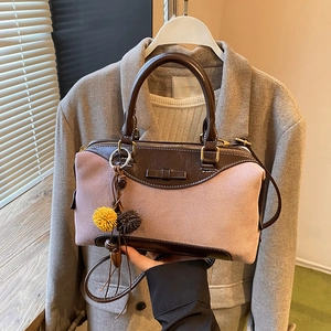 Pink suede and brown leather crossbody bag with a bow and pom-pom charms in hand