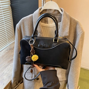 Retro black Boston handbag with bow detail and yellow charm on a gray blazer background