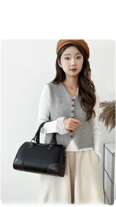 Detail of black pebbled leather boston bag with brown corner guards and rivet accents