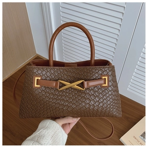 Close-up of brown woven texture handbag with golden X metal buckle and round handles