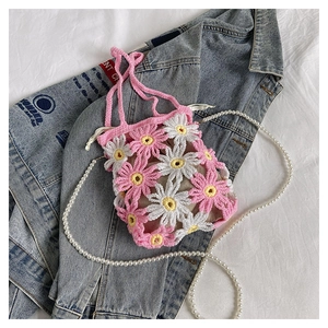 Detail of pink and white handmade crochet daisy bag with pearl strap on denim