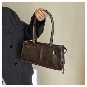Detailed view of deep brown glossy leather handbag with elegant golden buckles and sleek handles