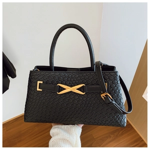 Detail of black woven texture leather bag with gold X-shaped metal buckle and round handle