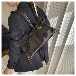 Close-up of a vintage dark brown glossy shoulder bag with elegant gold metal buckle details