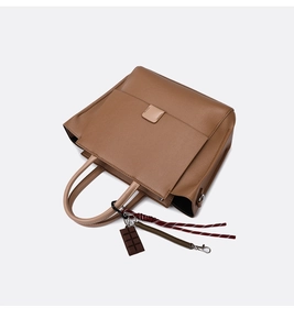 Detail van bruine leren shopper met chocoladebedeltje en tweekleurige handvatten in kleurblok