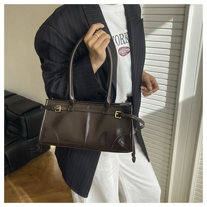 Detail view of deep brown glossy leather handbag with golden buckles and fine straps