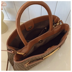 Detail of woven leather tote bag with three compartments and gold magnetic buckle