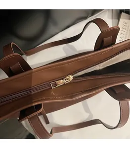 Close-up of golden metal zipper and smooth stitching on the brown leather tote bag