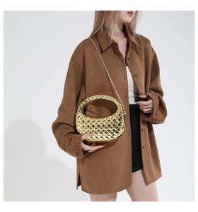 Detail of gold woven metal hobo bag with sleek chain strap shown on a model