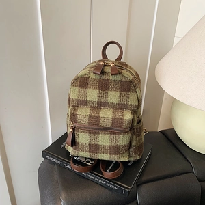 Zaino di peluche a scacchi verdi con rifiniture in pelle in un ambiente vintage raffinato