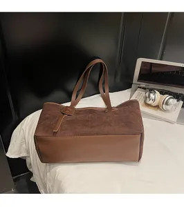 Detail of large brown suede tote bag with leather handles in a home office setting