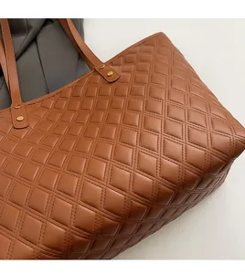 Dettaglio della borsa shopper marrone trapuntata con rivetti dorati e trama in pelle