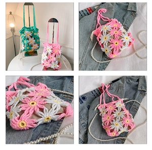 Macro detail of handmade crochet daisy bucket bag with white floral pattern and pearl chain