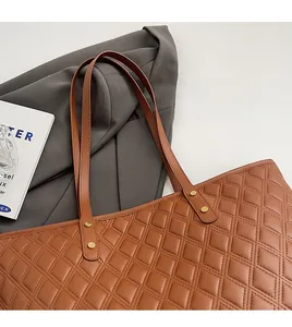 Dettaglio ravvicinato di una borsa tote marrone trapuntata con rivetti dorati e tracolle eleganti