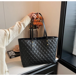 Borsa tote trapuntata nera con borchie dorate presentata in un ambiente lifestyle elegante