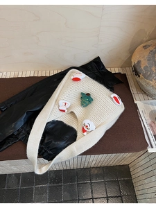 Detail of off-white knitted tote bag featuring plush Santa and Christmas tree patches
