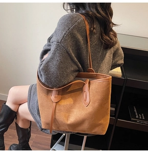 Detail of a large brown suede tote bag featuring long shoulder straps for daily commuting