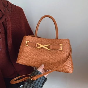 Caramel brown woven textured handbag with gold X-buckle and adjustable crossbody strap