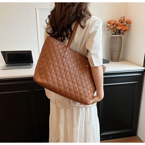 Borsa tote trapuntata marrone con fibbia dorata sulla scrivania in un ambiente da ufficio