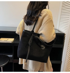 Minimalist black suede tote bag with leather knot detail shown on model shoulder