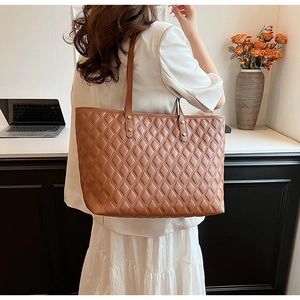 Dettaglio di una borsa tote trapuntata marrone con finiture metalliche dorate