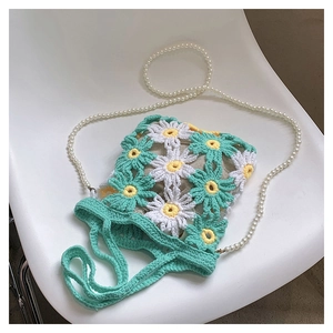 Detail of handmade crochet flower bag featuring daisy patterns and pearl strap