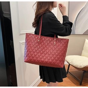 Dettaglio della borsa tote trapuntata bordeaux con borchie dorate e spalline sottili