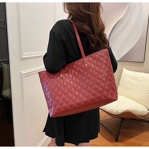 Dettaglio della borsa tote in pelle rosso scuro con cuciture trapuntate e rivetti d'oro