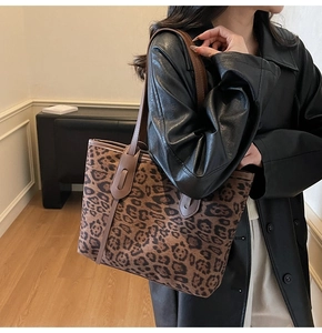 Close-up of leopard print tote bag with brown straps worn by a model in leather coat