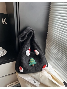 Detail of black knit tote bag with 3D Santa and Christmas tree embroidery in cozy home setting