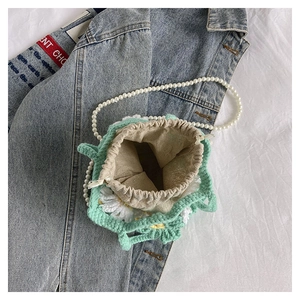 Detail of mint green crochet bucket bag with daisy patterns and pearl strap
