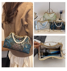 Detail of vintage embroidered floral handbag with pearl handle and metal chain strap