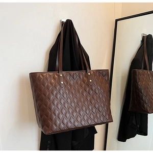 Dettaglio della borsa tote trapuntata marrone scuro con grande capacità e trama in pelle