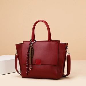 Deep red pebbled leather tote bag with top handles and a colorful braided tassel charm