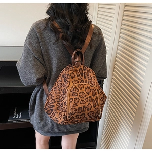 Détail d'un sac à dos imprimé léopard avec fermetures dorées et bretelles en tissu brun