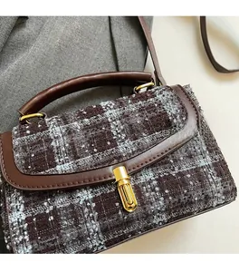 Gros plan d'un sac à main vintage en tweed marron avec boucle dorée et poignée en cuir