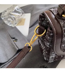Détail de la ferrure dorée et du tissu en tweed sur un sac à bandoulière vintage