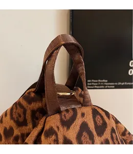 Détail d'un sac à dos imprimé léopard avec poignée en nylon brun et ferrures dorées