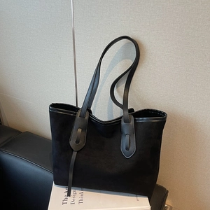 Minimalist black leopard-lined tote bag in premium suede shown on a leather sofa