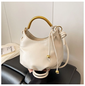 Detail of cream white cloud bag featuring elegant gold metal handle and luxury bead decor