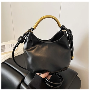 Detail of black leather cloud bag featuring a curved gold metal handle and pleated bottom