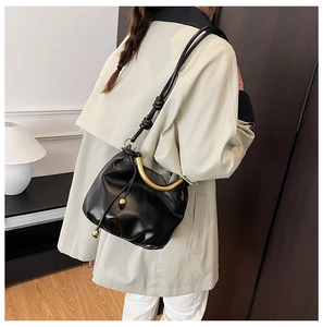 Detail of black pleated cloud bag with curved gold handle and side drawstring charms