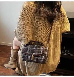 Détail d'un sac bandoulière rétro en tweed avec fermoir métallique doré et cuir brun