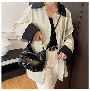 Detail of black pleated cloud bag featuring a vintage gold circular metal handle
