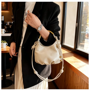 Detail of soft cream cloud bag with gold ring handle and knotted beaded strap detail