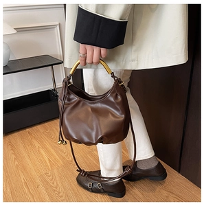 Detail of dark brown pleated cloud bag with golden handle and leather shoulder strap