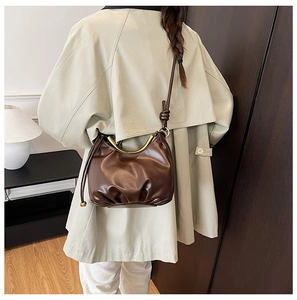 Brown leather cloud bag with gold handle styled with a khaki trench coat