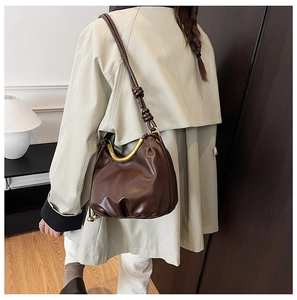 Detail of dark brown cloud bag with U-shaped gold handle and knotted strap detail