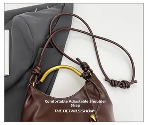Detail of adjustable knotted leather strap and golden metal handle on brown handbag